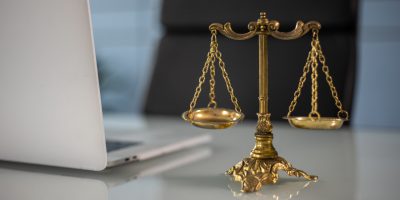 Computador e balança da justiça que representam o curso de direito EaD que pode começar a ser ofertado