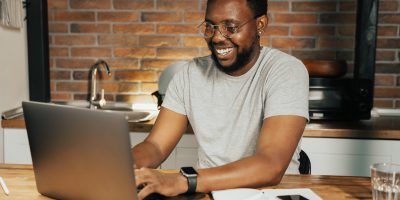 Homem estudando em um computador enquanto sorri
